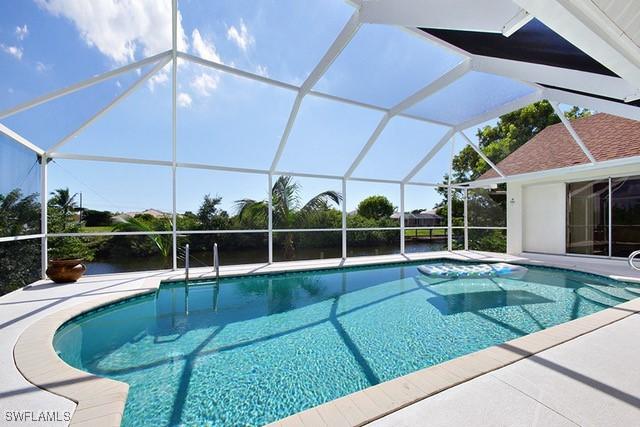 outdoor pool featuring glass enclosure and a patio