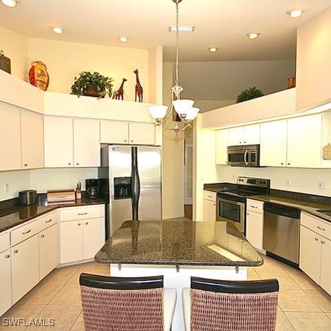 kitchen featuring stainless steel appliances, hanging light fixtures, dark countertops, and white cabinets