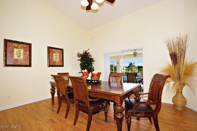 dining area featuring ceiling fan, high vaulted ceiling, and wood finished floors