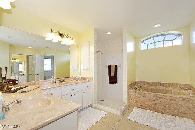 bathroom with a sink, a bath, tile patterned floors, double vanity, and walk in shower