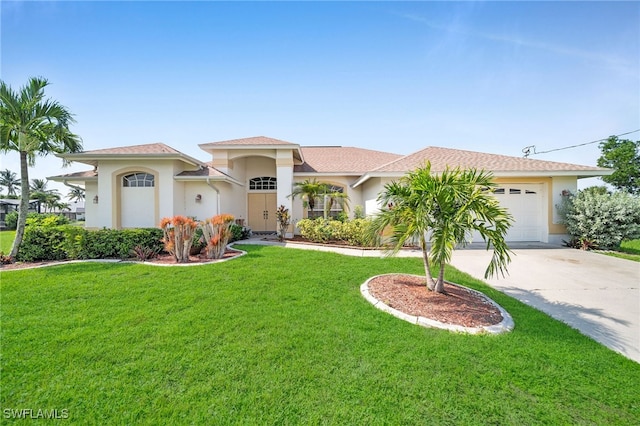 mediterranean / spanish house with a front yard, driveway, an attached garage, and stucco siding