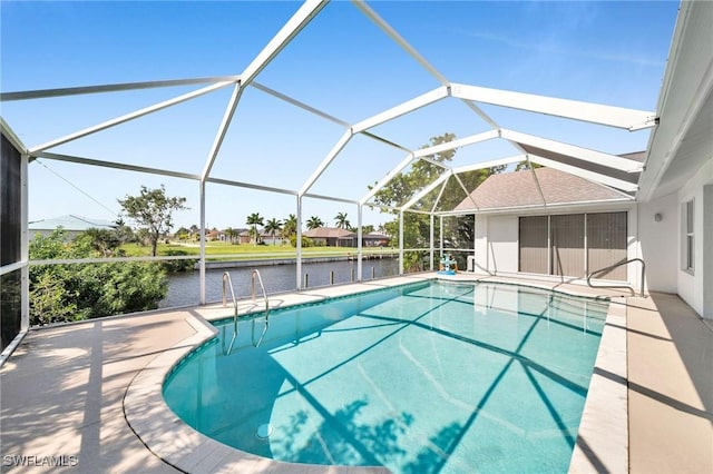 pool with a patio area, glass enclosure, and a water view