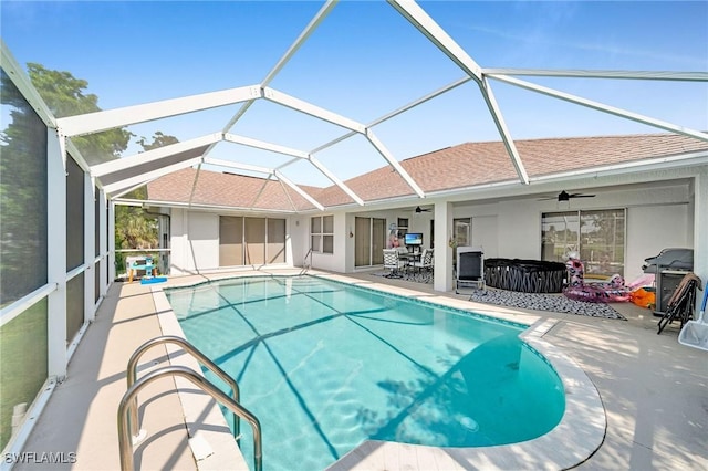 pool with glass enclosure, ceiling fan, and a patio