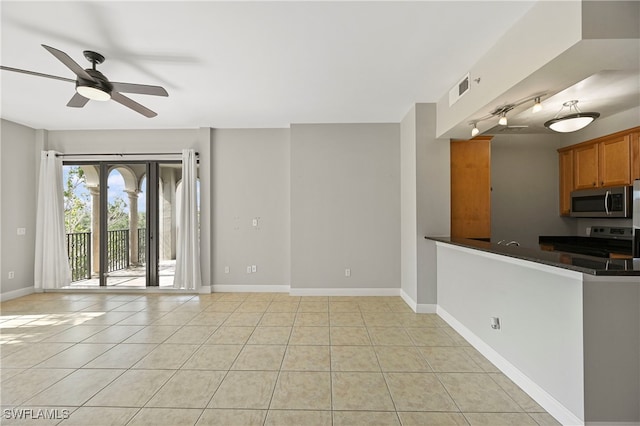 interior space featuring a ceiling fan, light tile patterned flooring, visible vents, and baseboards