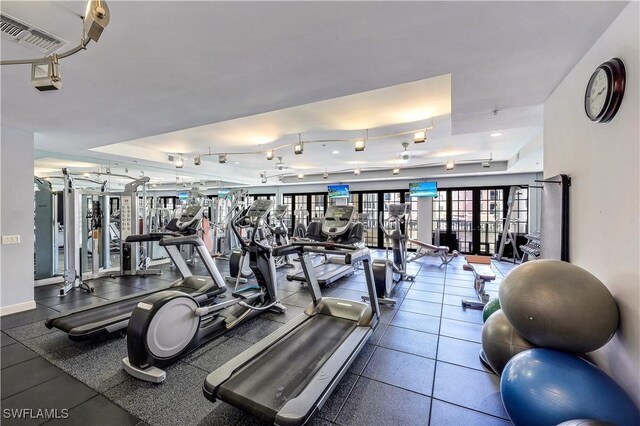 workout area featuring tile patterned floors, track lighting, french doors, and a tray ceiling