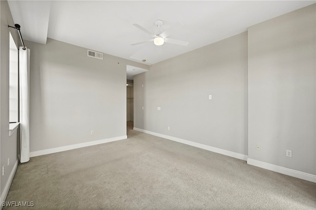 carpeted empty room with a ceiling fan, visible vents, and baseboards