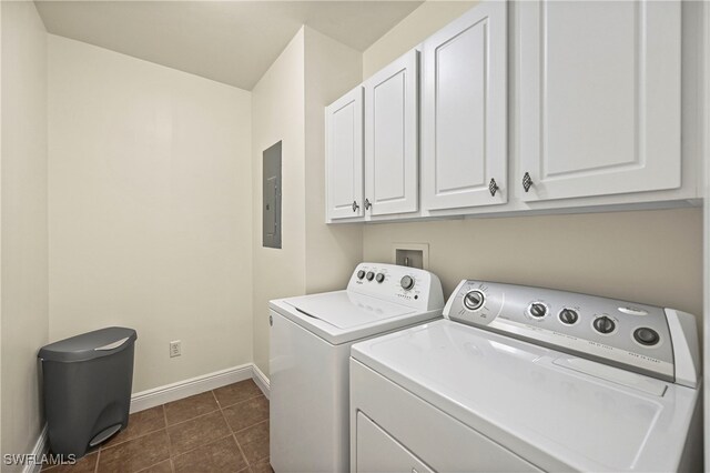 clothes washing area with washing machine and dryer, cabinets, dark tile patterned floors, and electric panel