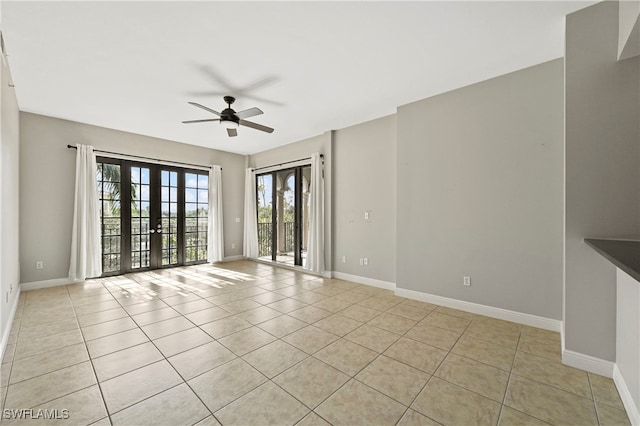 empty room featuring light tile patterned flooring, ceiling fan, baseboards, and french doors