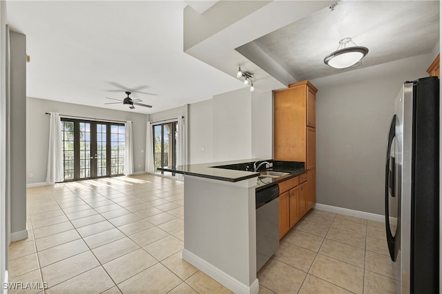 kitchen with dark countertops, appliances with stainless steel finishes, open floor plan, a peninsula, and light tile patterned flooring