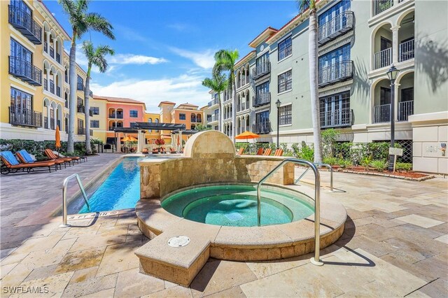 view of pool with a community hot tub, a pergola, and a patio area