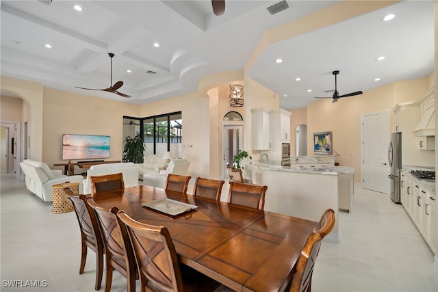 dining area featuring beam ceiling, ceiling fan, coffered ceiling, and sink