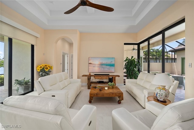 living room featuring ceiling fan and a tray ceiling