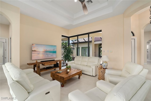 living room featuring a tray ceiling, ceiling fan, and a towering ceiling