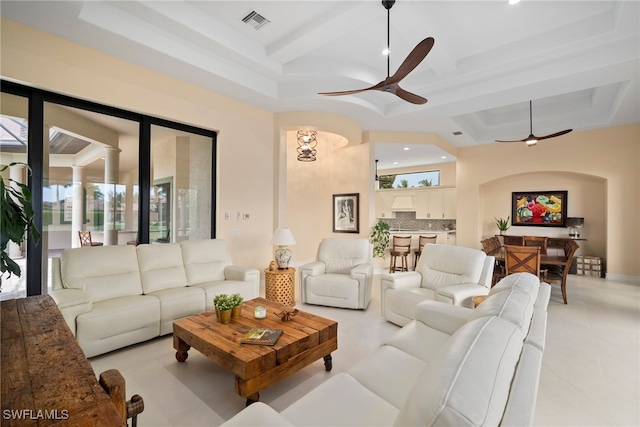 living room with a tray ceiling, ceiling fan, and light tile patterned floors