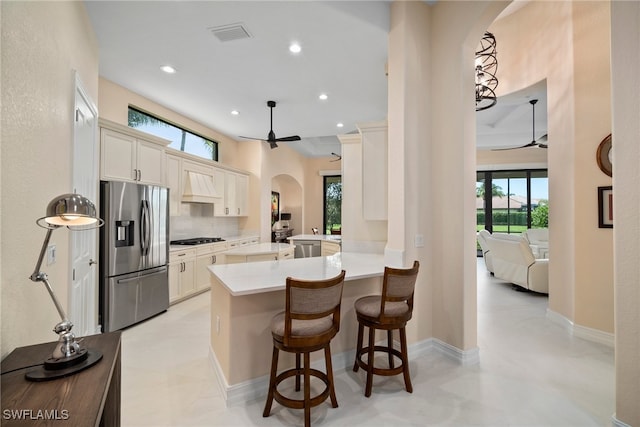 kitchen featuring kitchen peninsula, appliances with stainless steel finishes, tasteful backsplash, ceiling fan, and a breakfast bar area