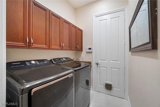 washroom with washing machine and clothes dryer and cabinets