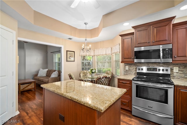 kitchen featuring ceiling fan with notable chandelier, stainless steel appliances, dark hardwood / wood-style flooring, a center island, and backsplash