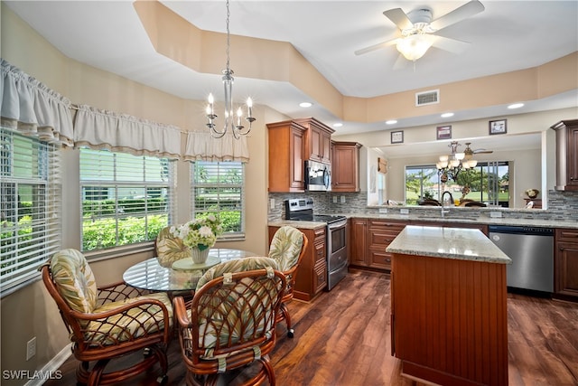 kitchen with stainless steel appliances, sink, light stone counters, a center island, and dark wood-type flooring