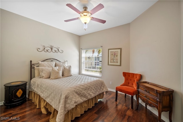 bedroom with a wood stove, dark wood-type flooring, and ceiling fan