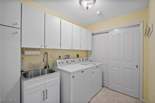 washroom featuring washing machine and dryer, cabinets, sink, and light tile patterned floors