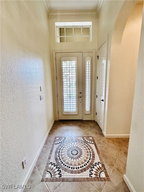 foyer entrance with ornamental molding and light tile patterned floors