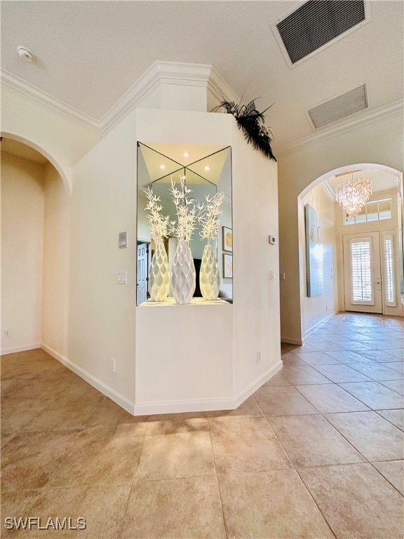 hall featuring tile patterned floors, a chandelier, and ornamental molding