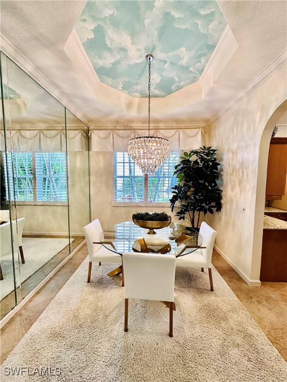 sitting room with an inviting chandelier, a tray ceiling, and ornamental molding