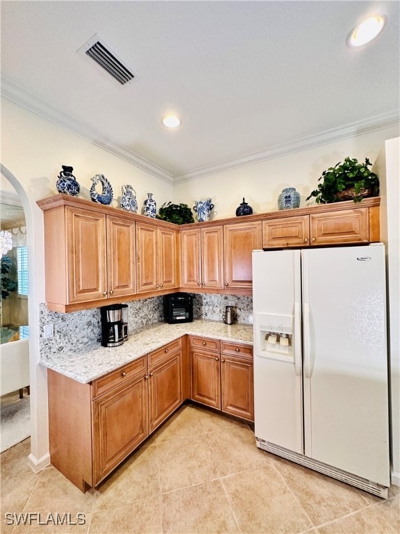 kitchen featuring decorative backsplash, white refrigerator with ice dispenser, crown molding, and light tile patterned floors