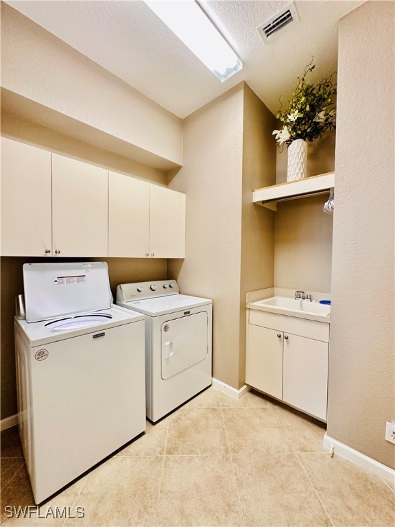 washroom featuring sink, separate washer and dryer, cabinets, a textured ceiling, and light tile patterned floors