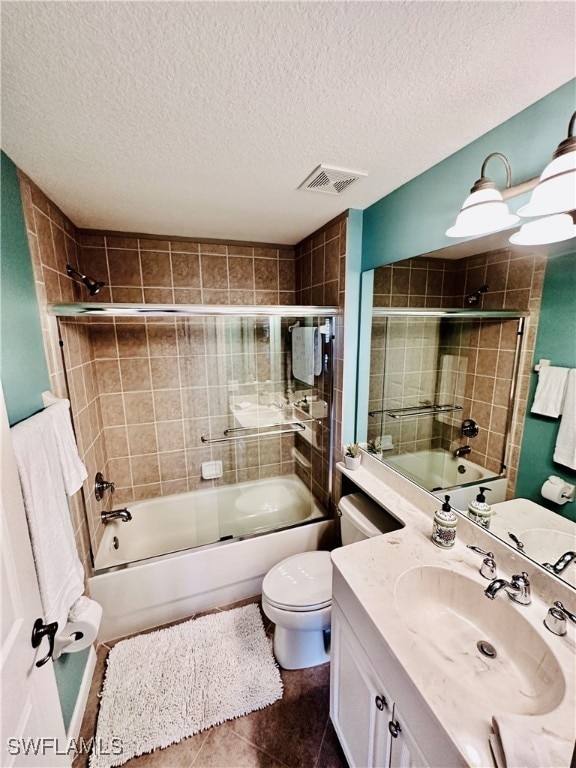 full bathroom with tile patterned flooring, bath / shower combo with glass door, a textured ceiling, toilet, and vanity