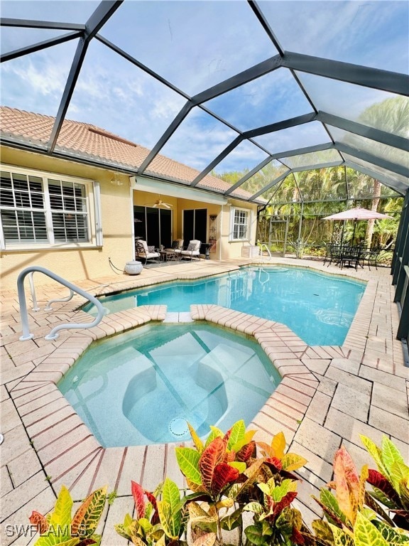 view of pool with an in ground hot tub, a patio, and glass enclosure