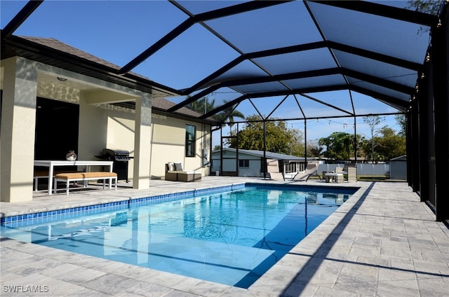 view of swimming pool featuring a patio area, grilling area, and glass enclosure