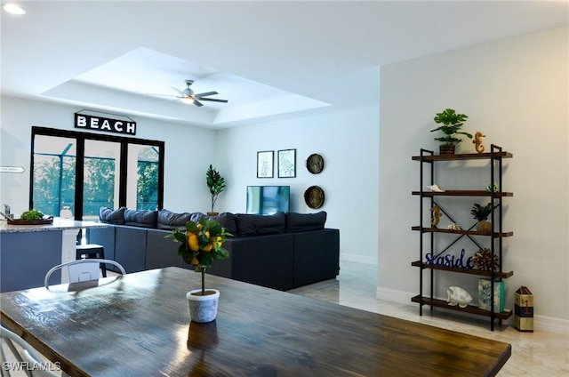 dining area with ceiling fan and a tray ceiling