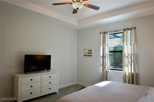 bedroom with carpet flooring, a tray ceiling, and ceiling fan