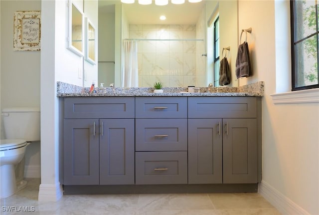 bathroom featuring toilet, a healthy amount of sunlight, vanity, and walk in shower