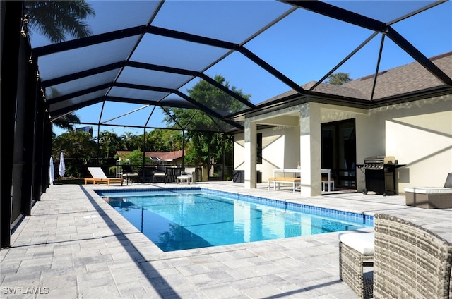 view of swimming pool featuring glass enclosure, a patio, and grilling area