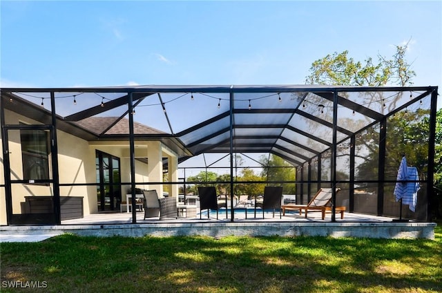 back of house featuring a patio area, glass enclosure, and a lawn