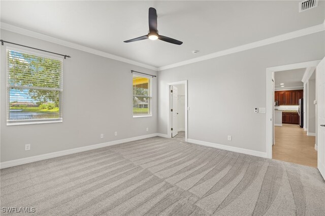 unfurnished room with light carpet, crown molding, and plenty of natural light