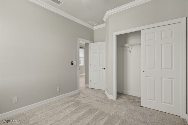 unfurnished bedroom featuring crown molding, a closet, and light colored carpet