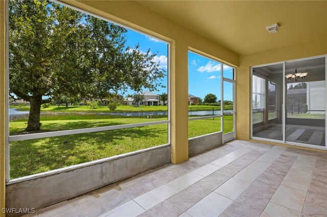 unfurnished sunroom featuring a water view and a chandelier