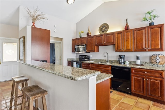 kitchen with a breakfast bar area, light tile patterned floors, black appliances, light stone countertops, and sink