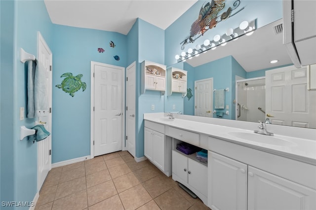 bathroom with a shower with shower door, double sink vanity, and tile patterned flooring