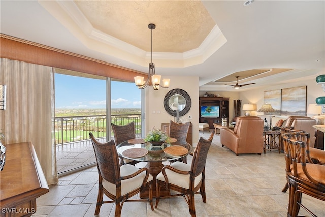 dining space featuring ornamental molding, ceiling fan with notable chandelier, and a tray ceiling