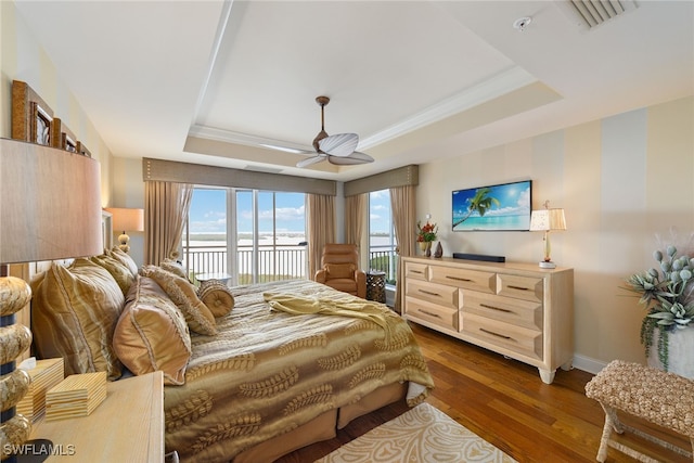 bedroom featuring dark wood-type flooring, ceiling fan, a raised ceiling, and access to outside