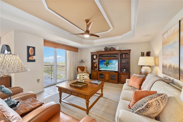 living room with ceiling fan and a raised ceiling