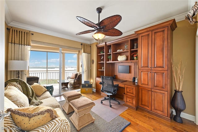 office featuring light hardwood / wood-style floors, ceiling fan, a water view, and ornamental molding