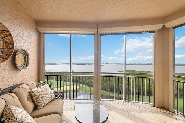 sunroom featuring a wealth of natural light and a water view