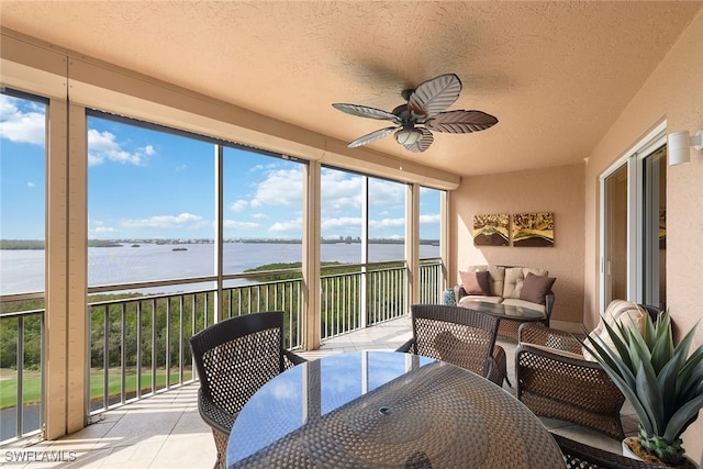 sunroom / solarium featuring a water view and ceiling fan