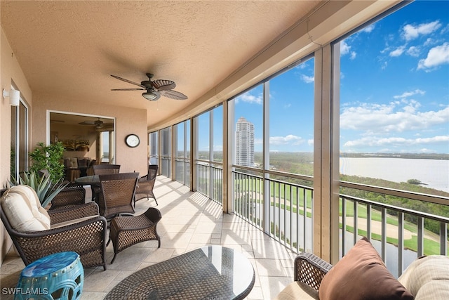 sunroom / solarium with a water view and ceiling fan