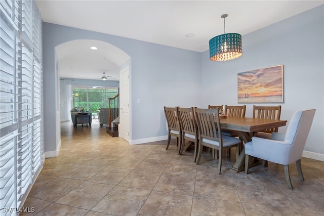 tiled dining room featuring ceiling fan with notable chandelier